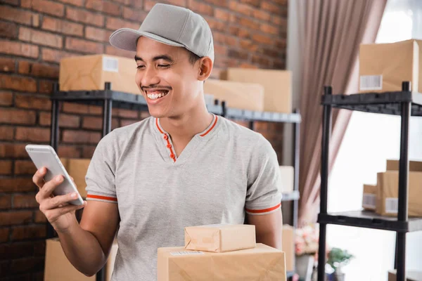 man with package holding smartphone