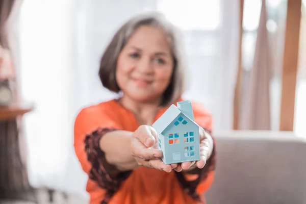 Starsza kobieta trzymając house symbol — Zdjęcie stockowe