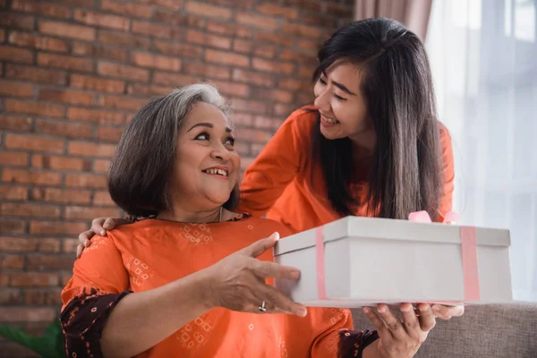 Mulher dando presente para sua mãe idosa — Fotografia de Stock