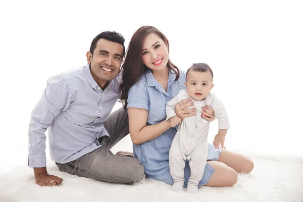 Feliz familia con lindo hijo sentado en el suelo mientras sonríe en —  Fotos de Stock
