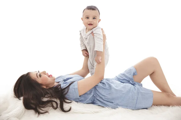 Beautiful mom playing with her cute son while lying on the bed — Stock Photo, Image