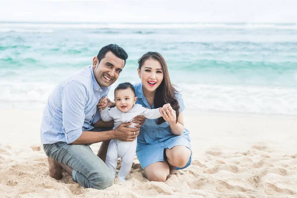 Feliz pequeña familia sonriendo en la cámara mientras que las vacaciones en la playa —  Fotos de Stock