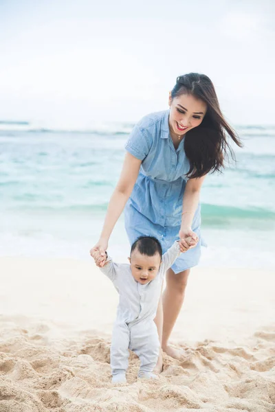 Belle mère enseigne à son fils marche sur la plage — Photo