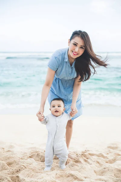 Hermosa madre está enseñando a su hijo camina en la playa —  Fotos de Stock