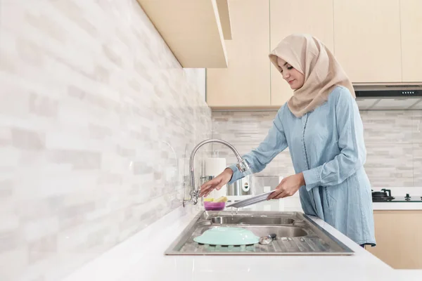 Hermosa joven con hijab lavando los platos —  Fotos de Stock
