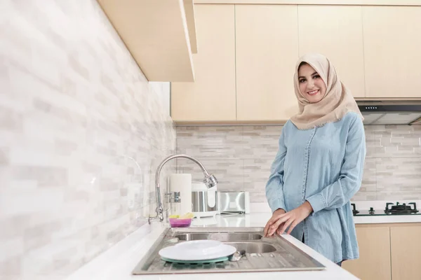 Красивая молодая женщина в хиджабе моет посуду — стоковое фото