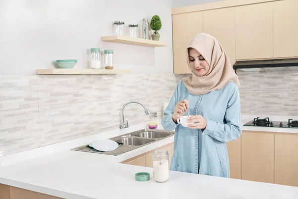 Красивая молодая женщина в хиджабе добавляет сахар в чашку чая — стоковое фото