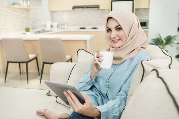 Mooie jonge vrouw die het dragen van hijab drinken een kopje thee terwijl — Stockfoto