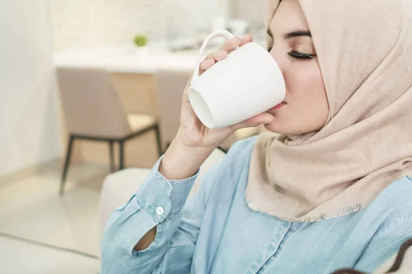 Schöne junge Frau im Hijab trinkt eine Tasse Tee bei liv — Stockfoto