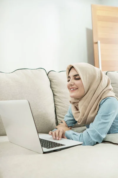 Bella casalinga indossa hijab godere la navigazione sul computer portatile in un — Foto Stock