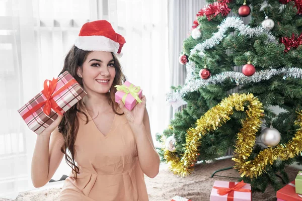 Hermosa mujer casual con sombrero de santas sentado mientras sostiene —  Fotos de Stock