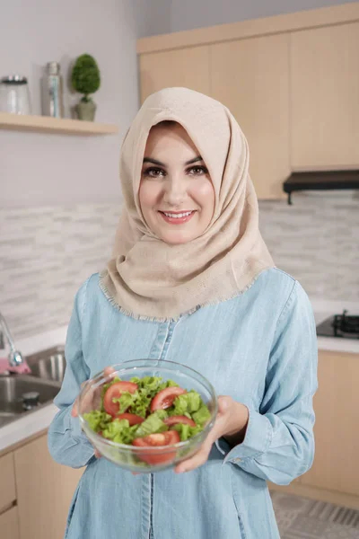 Bela jovem mulher vestindo hijab preparando salada vegetal em — Fotografia de Stock
