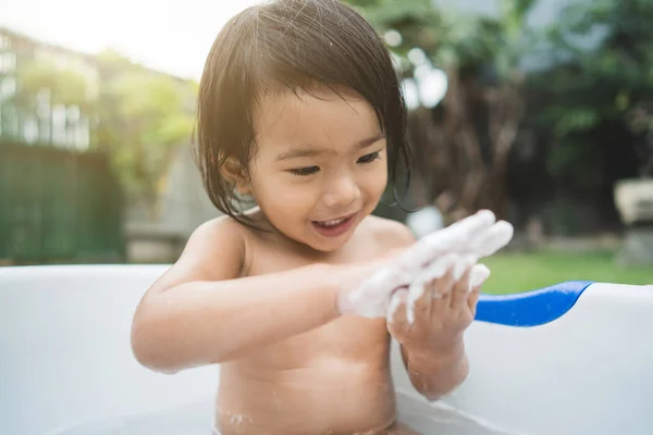 Menina bonita feliz tomar um banho em um tubo de banho do bebê — Fotografia de Stock