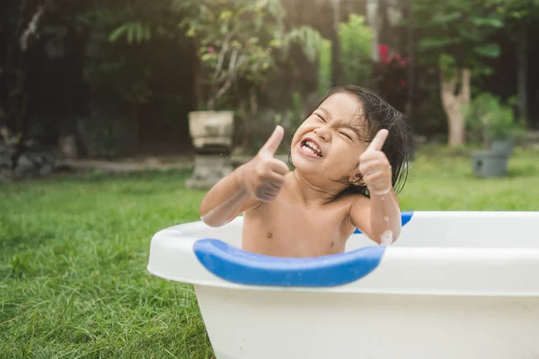 Menina bonita feliz tomar um banho em um tubo de banho do bebê enquanto — Fotografia de Stock