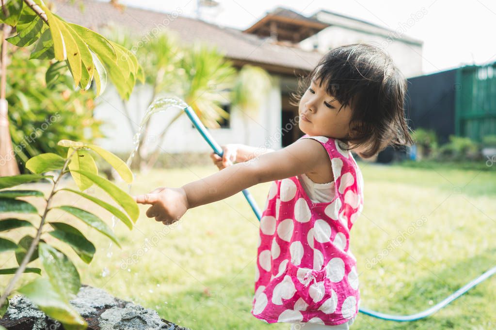 beautiful little child watering the plants