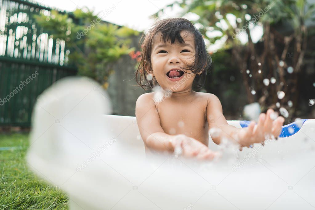happy beautiful baby girl take a bath in a baby bath tube