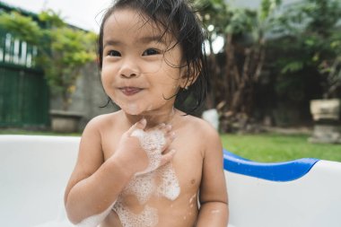 güzel kız bebek almak bir banyo ve bir bebek sabun köpüğü oynarken