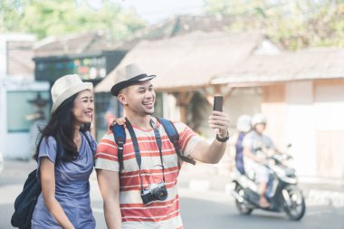 iki genç backpackers mobilephones kamera kullanarak selfies alarak