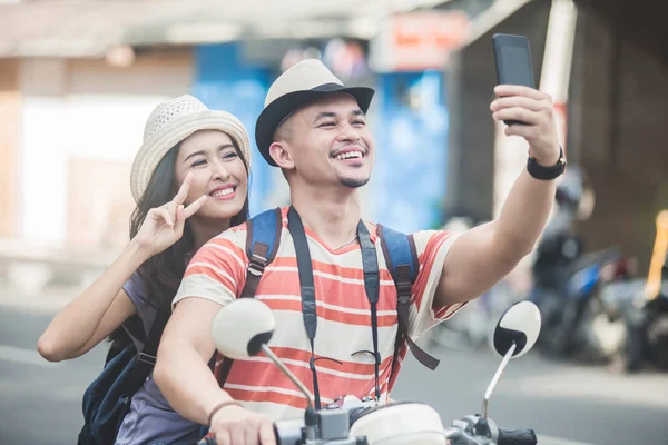 Two young backpackers taking selfies using mobilephones camera w — Stock Photo, Image