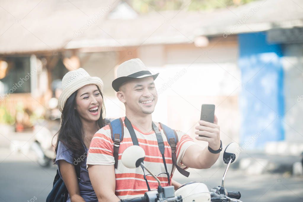 two young backpackers taking selfies using mobilephones camera w