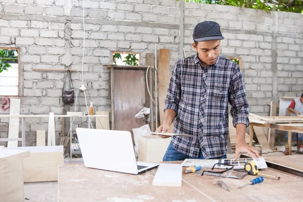 Giovane falegname verifica campioni di materiale utilizzando internet su lapt — Foto Stock