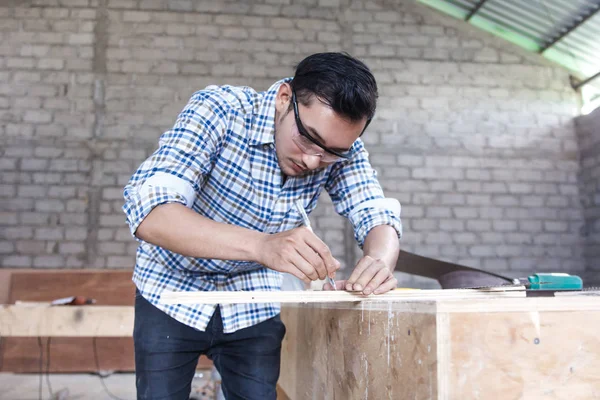 Carpintero joven que mide y marca el tablero de madera —  Fotos de Stock