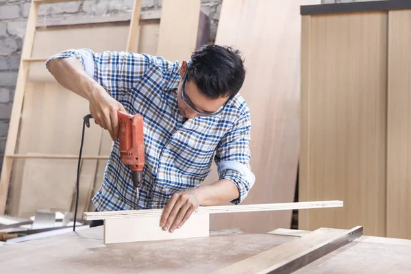 worker at carpenter work shop installing bolts using screwdriver