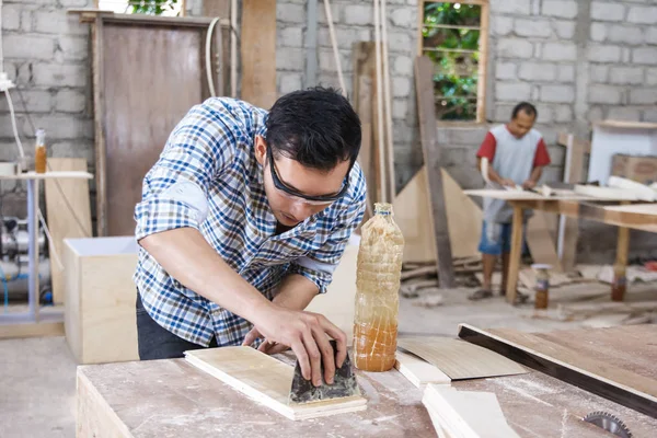 Trabajador en el espacio de trabajo del carpintero aplicando vinilo de madera en un tablero u —  Fotos de Stock