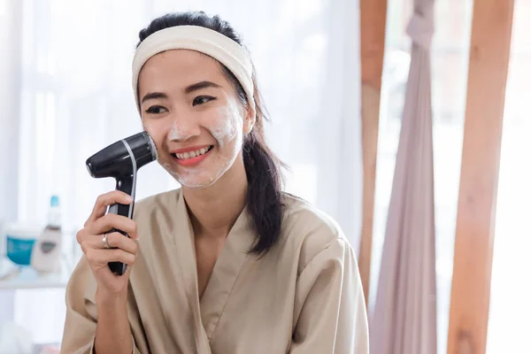 Азиатская женщина с помощью электрической мойки лица — стоковое фото