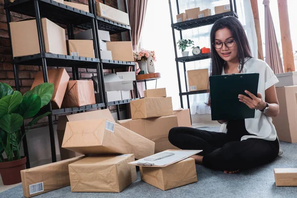 Aziatische vrouw controleren verzendkosten pakketten — Stockfoto