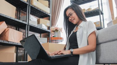 Teslimat paketleri işleme genç işkadını gözlüklü online iş evde, evde, dizüstü iş kullanma