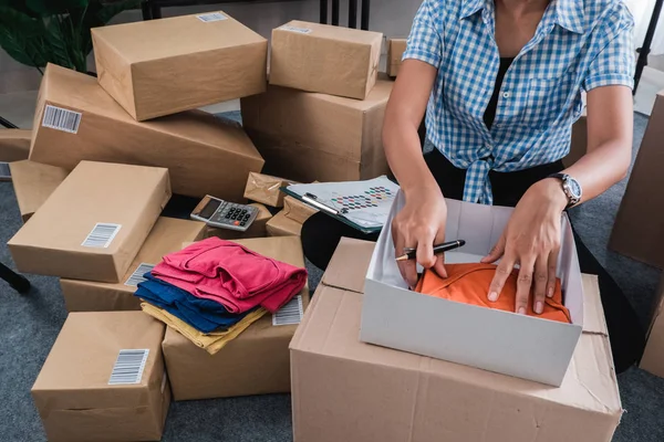 Jovem mulher embalagem de roupas colocar nas caixas — Fotografia de Stock