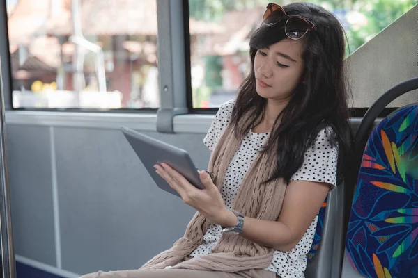 Молодая женщина использует свой цифровой планшет в автобусе — стоковое фото