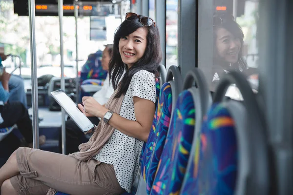 バス笑顔に彼女のデジタル タブレットを使用してカメラを探している若い女性 — ストック写真