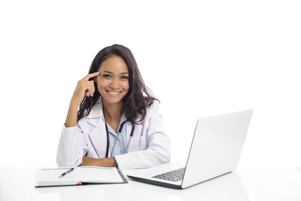 Asiatisk ung läkare leende medan du sitter på hennes arbetsyta — Stockfoto