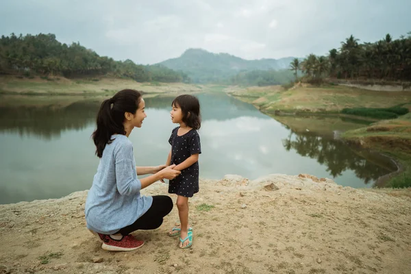 A mother and his daughter on the edge of the lake, talk about ho — Stock Photo, Image