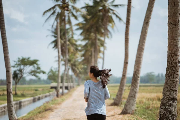 A woman ran in side coconut trees — Stock Photo, Image