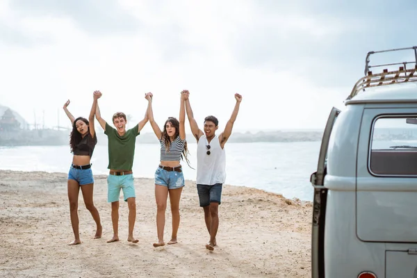 Amigos felizes andando na praia e levantar as mãos — Fotografia de Stock