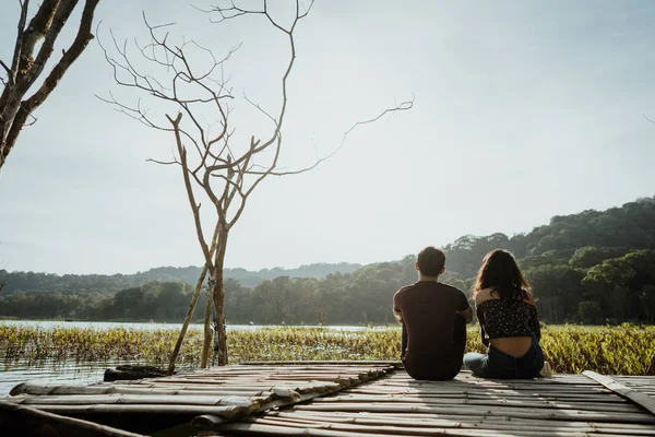Casal sentado em uma tábua de madeira flutuante em um lago — Fotografia de Stock