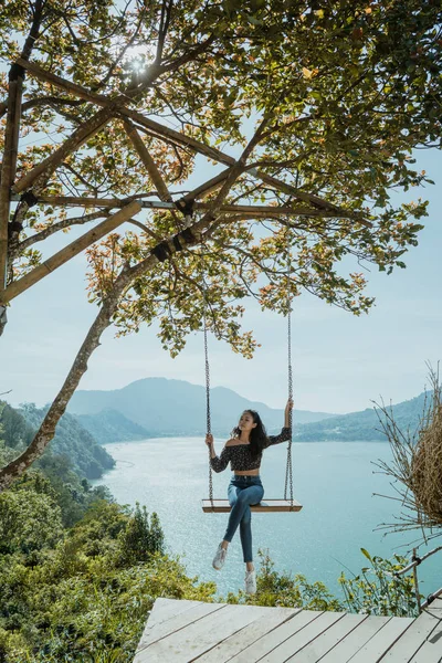 Retrato de mujer disfrutando de la naturaleza desde la cima de una colina sentada en un swin —  Fotos de Stock