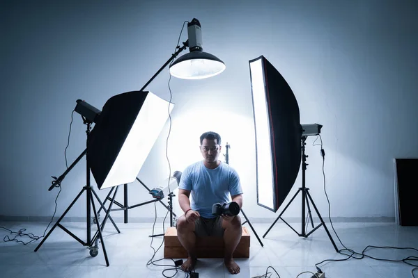 Fotógrafo masculino en estudio de fotografía rodeado de equipos de iluminación —  Fotos de Stock