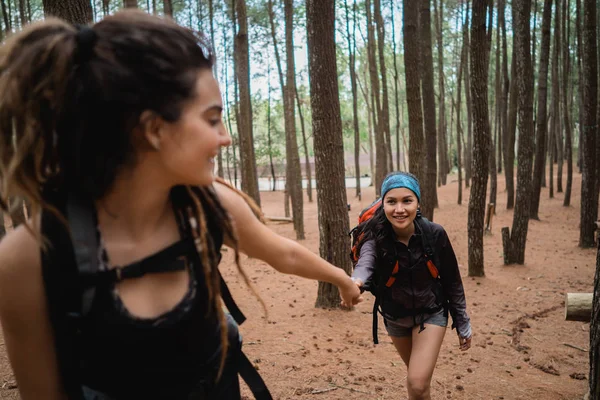young female hiker helping friend while trekking
