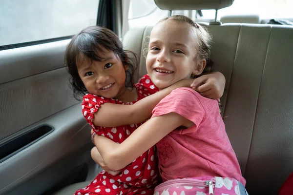 Μικτή φυλή παιδί Αγκαλιάζοντας κάθε άλλο ενώ κάθεται σε ένα αυτοκίνητο — Φωτογραφία Αρχείου