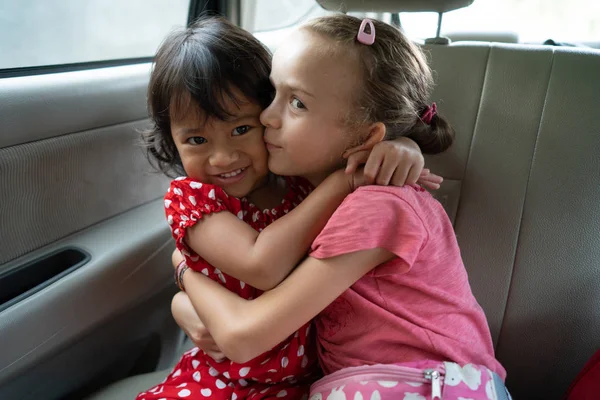 Blandad ras kid omfamnar varandra medan du sitter i en bil — Stockfoto