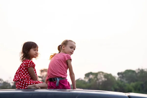 車の上に座って夕日を楽しむ子どもたち — ストック写真