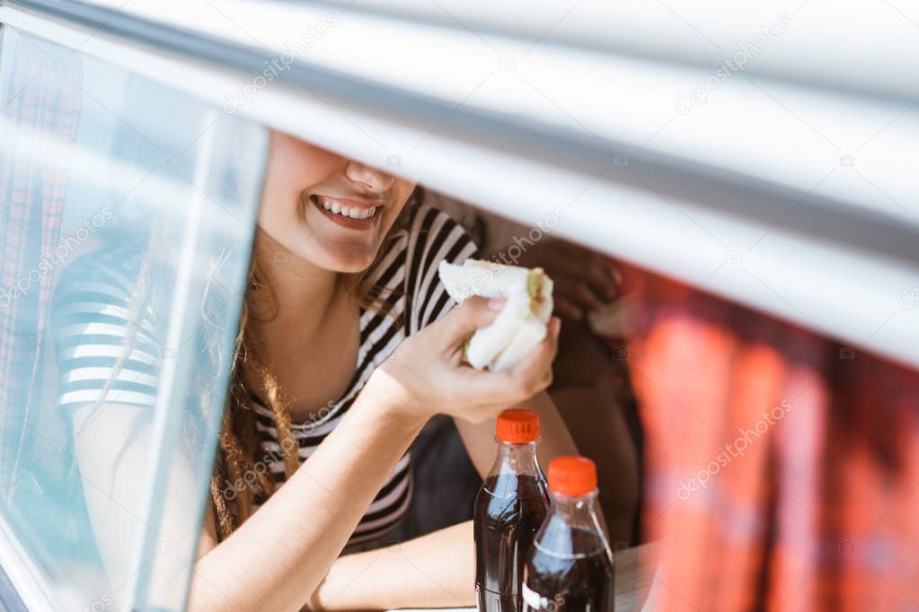 seen in the window young woman sitting enjoy a sandwich breakfas