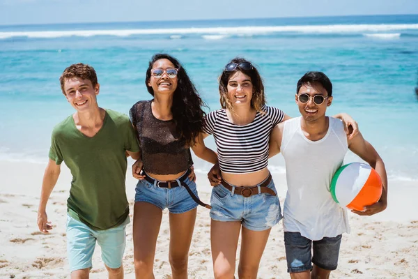 Group of cheerful young people walking together hold a ball — Stock Photo, Image
