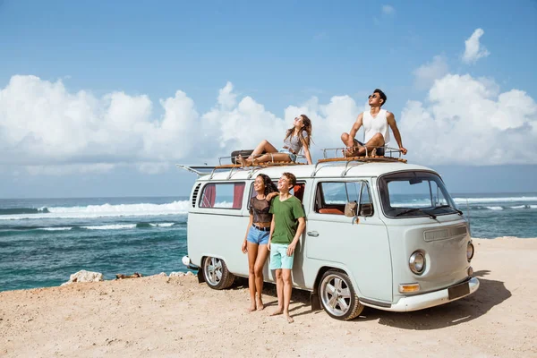 Hipster girl relaxing with friends on the retro van roof