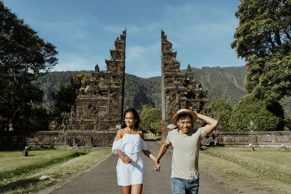 couple running together through bali traditional gate