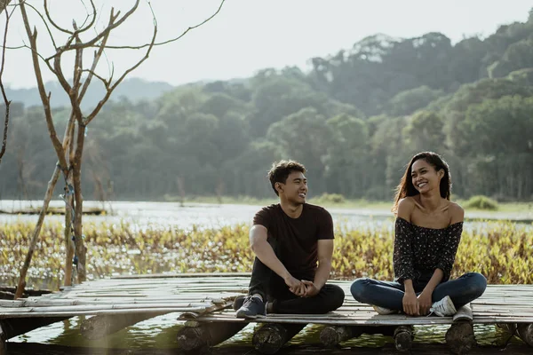 Couple assis sur une planche de bois flottant sur un lac — Photo